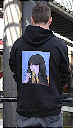 Kanada-Ya | Ramen Near Me | A person is standing with their back to the camera, wearing a Noodle Girl Hoodie featuring a stylized illustration of a long-haired figure holding a yellow object, set against parts of a bridge structure. | London